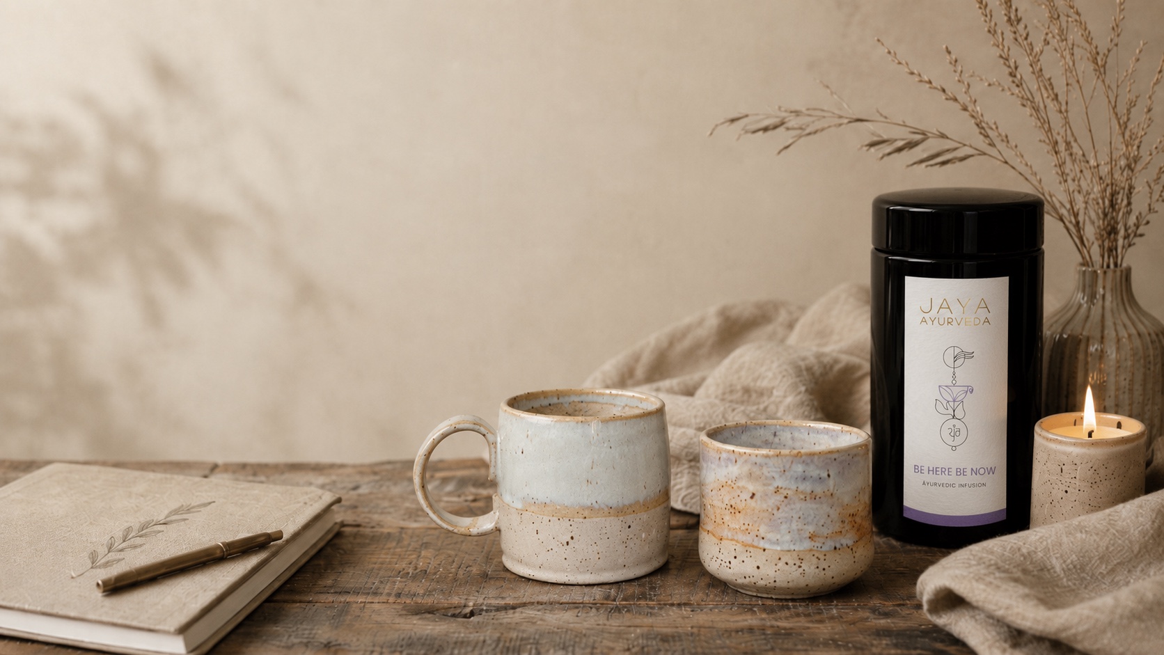 Handmade pottery mugs, a journal and a Jaya Ayurveda infusion arranged for a quiet ritual